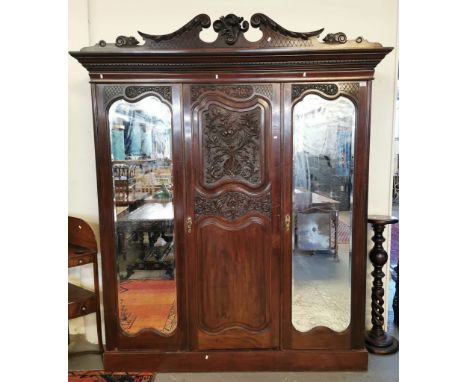 Edwardian stained mahogany three door mirrored ornately carved wardrobe, on a platform base. (B.P. 21% + VAT)