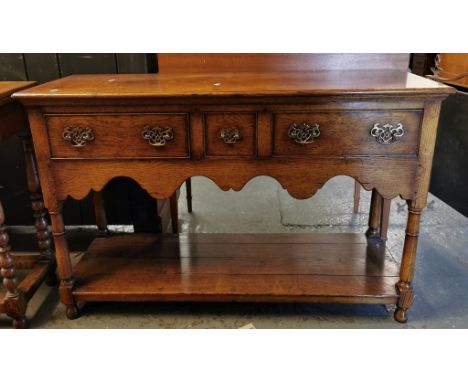 Gwilym C Price, reproduction oak dresser base, the moulded top above three cock beaded drawers, with shaped frieze on baluste