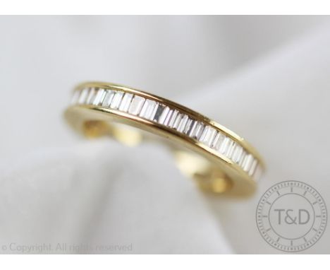 A diamond set full eternity ring, set throughout with channel set baguette cut diamonds, all set in yellow metal stamped 'K18