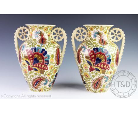 A pair of Fisher of Budapest twin handled vases, decorated with Persian inspired flowers in the manner of Zsolnay, 26cm, (one
