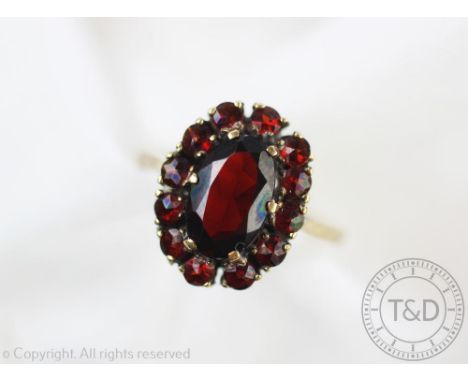 A garnet set oval cluster ring, all set in yellow metal, hoop stamped '333', weight 4.5gms, size R
