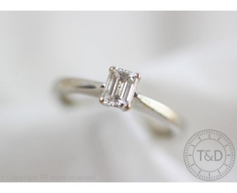 A diamond solitaire ring, the 18ct white gold ring set with a single emerald cut diamond within four claw setting, hoop stamp