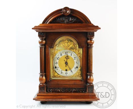 A late Victorian carved walnut eight day mantel clock, with silvered Arabic numeral chapter ring and German movement striking