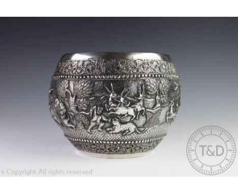 A large Burmese silver bowl, embossed profusely in high relief with a continuous hunting scene of elephants, huntsman, wild b