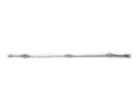 A white gold and colourless gem set bracelet, in a bar link design, spaced with three cluster divisions at intervals, on a sn