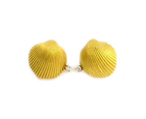 A pair of gold and diamond set earclips, each designed as a scallop shell, claw set with a circular cut diamond, detailed 18 