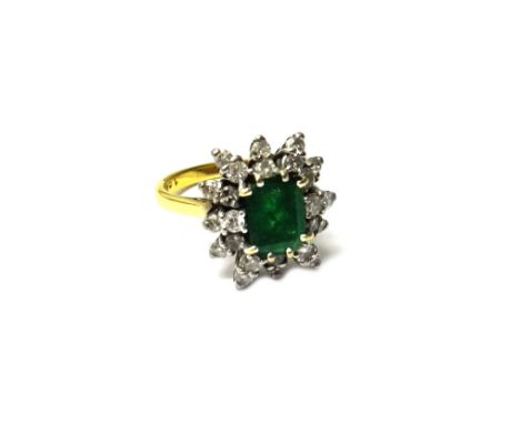 An 18ct gold, emerald and diamond set cluster ring, claw set with the cut cornered rectangular step cut emerald at the centre