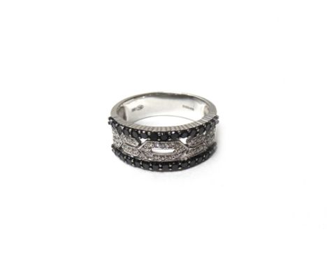 A white gold, diamond and black diamond set ring, the centre in a pierced geometric design, mounted with circular cut diamond