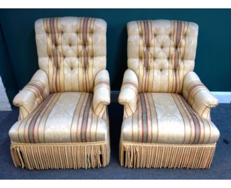 A pair of 20th century button back easy armchairs, each with straight front seat and tassel frieze, on turned stained beech s