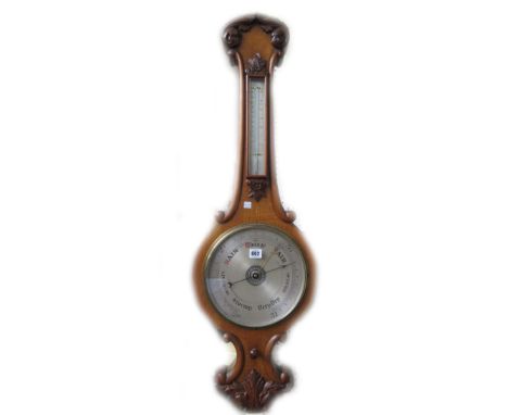 A Victorian oak cased wheel barometer with applied thermometer over a 9.5 inch silvered dial, with all over carved foliate de