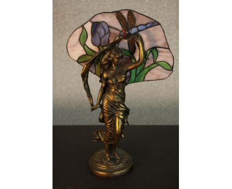 A Tiffany style table lamp, in the form of a maiden, with a stained glass shade to the rear depicting a dragonfly. H.43 W.27c