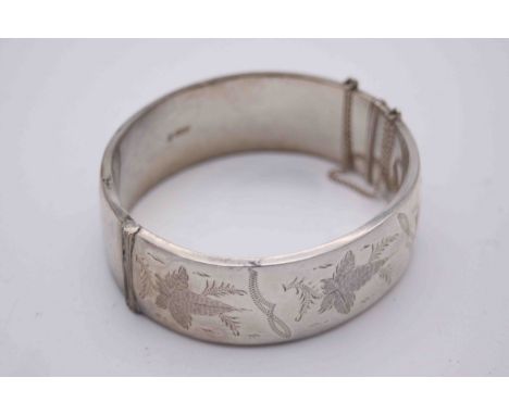 A silver wax filled engraved bangle with clip clasp and safety chain, decorated with a stylised ivy leaf design. Hallmarked: 