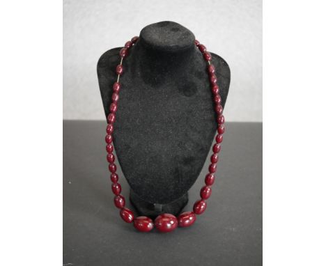 A vintage large cherry amber bakelite graduated bead necklace with screw barrel clasp. Weight 85g. L.60cm 