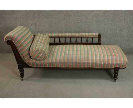 A late Victorian walnut chaise longue, upholstered in chequered fabric, with a bolster cushion, turned spindles to the arm, r