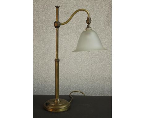 An early 20th century brass desk lamp, with an adjustable arm and a frosted glass shade, on a circular base. H.52 W.30cm. 