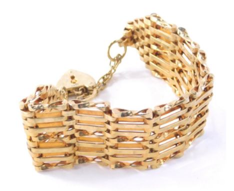 A gate bracelet, with eight bar link design safety chain and padlock, gold plated but stamped 15ct to chains and 18ct to padl