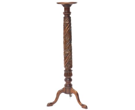 A mahogany torchere, the circular dished top above a leaf and spirally carved column on tripod base with pad feet, 129cm high