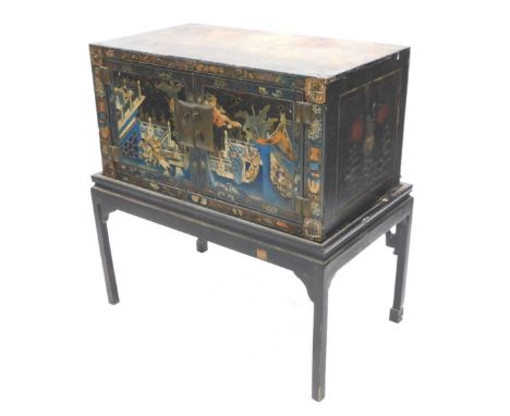 An antique Chinese lacquered commode cabinet, decorated with figures on horse back, buildings, etc. on a black ground, with t