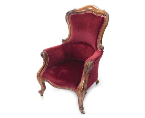 A Victorian mahogany show frame armchair with a padded back, arm rest and seat with scroll carved arm supports and legs and t