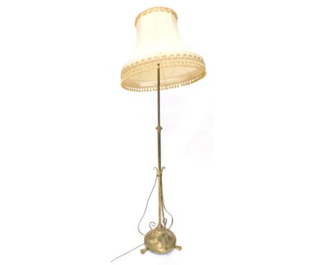 An early 20thC brass Art Nouveau floor lamp, with adjustable column the base with three scroll brackets on tapering feet with