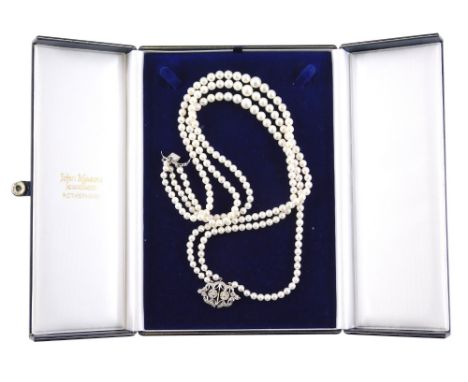 A three row pearl necklace, with pave set diamond clasp, in two floral clusters with outer wave design border, with three row