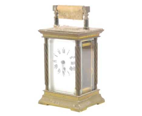 An early 20thC brass carriage clock, with five glass case, set with columns and swing handle, with a  Roman numeric dial and 