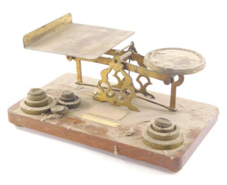 An early 20thC brass table scale, with fixed metal pans and a graduated of set of weights, 32cm wide.