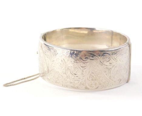 A 20thC silver hinged bangle, with heart engraved design of scrolls and vines, Birmingham 1949, engraved MBT, with safety cha