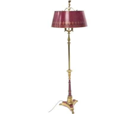 A French Empire style a standard lamp, with deep red and gilt shade, the bass with similar decoration applied with acanthus a