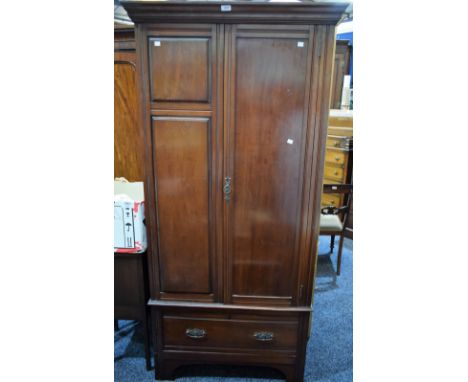 An early 20th century mahogany wardrobe, outswept cornice above a panel door enclosing an arrangement of hanging hooks, long 