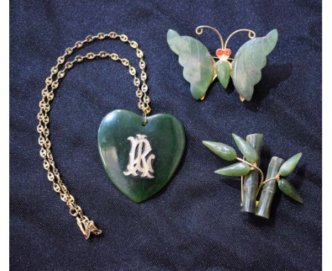 A green stone heart pendant, possibly jade, with applied initials RL, suspended from a gold plated chain necklace; similar ba