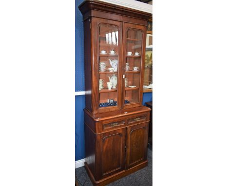 A late Victorian mahogany library bookcase, of narrow proportions, rounded cornice above a pair of glazed doors enclosing fou