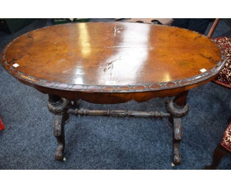 A Victorian walnut centre table, moulded elliptical top above a shaped frieze, cabriole legs, ceramic casters, 103cm wide