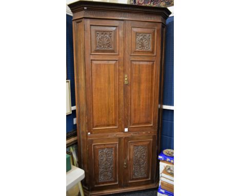 A substantial Country House oak floor standing corner cupboard, dentil cornice above a pair of raised and fielded panel doors