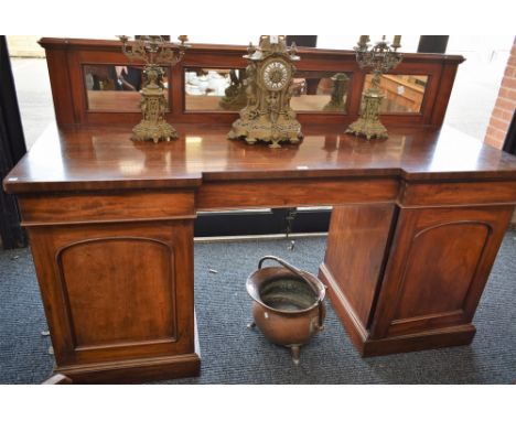 A Victorian mahogany sideboard, inverted break-centre top with mirrored half-gallery above three frieze drawers, each pedesta