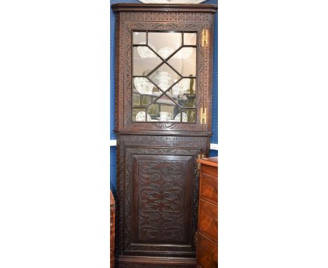 A 19th century oak floor standing corner vitrine/display cabinet, moulded cornice above a glazed door enclosing two shaped sh