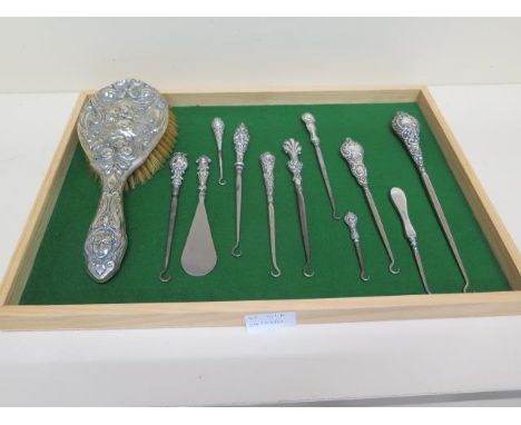 A collection of 10 silver/white metal handle button hooks, a shoe horn and a brush 