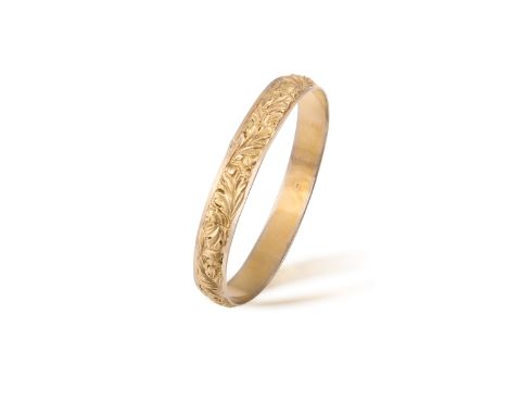 A GOLD BANGLEThe gold bangle decorated with scrolling flowers in relief throughout, in 18K gold, French assay marks, maker's 