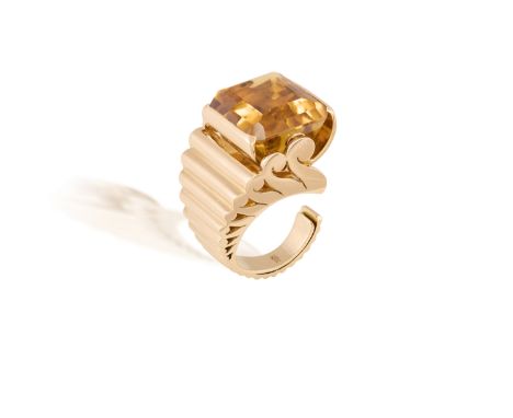 A CITRINE AND GOLD RETRO RING, CIRCA 1940The rectangular-cut citrine within a raised swing-boat setting mounted aloft of the 