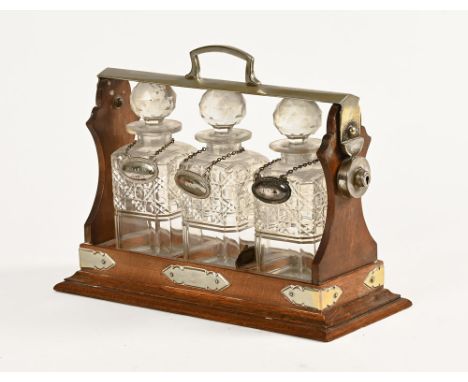 An oak tantalus stand, no makers marks with three decanters each with label.  Height 31 cm, width 39 cm.