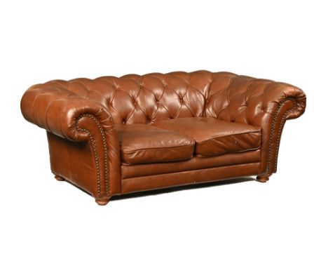 A tan leather Chesterfield settee, raised on turned wooden feet. Width 180 cm, depth 98 cm, seat height 40 cm.