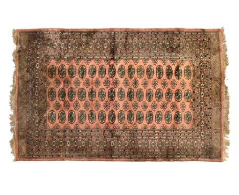 A vintage Persian rug, with pink ground, with repeating border and central Gul design.  200 x 132 cm.