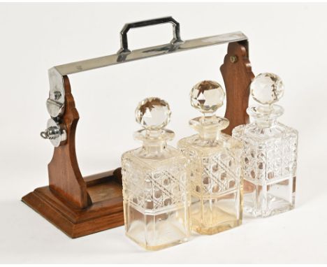 An Edwardian oak three decanter tantalus, with plated locking mechanism, no makers mark.