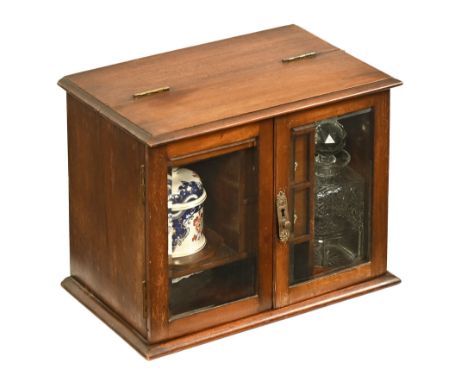 A Victorian smokers cabinet, with a hinged lid and pair of bevelled glass doors opening to a fitted interior with decanters, 