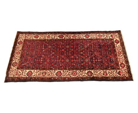 A Persian rectangular rug, with red and blue ground and cream border and decorated with floral panels. 328 x 159 cm.