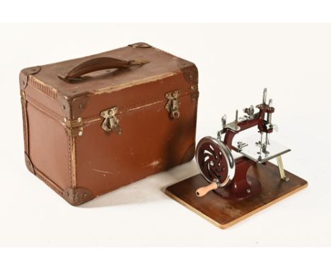 A cased child's hand operated sewing machine. 