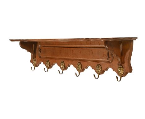 A continental oak coat rack, with integral shelf and metal gilded hooks depicting two figures.  Height 22 cm, width 114 cm, d