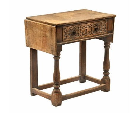 An oak side table, with flap to either side and carved single drawer raised on turned legs united by stretchers.  Height 75.5