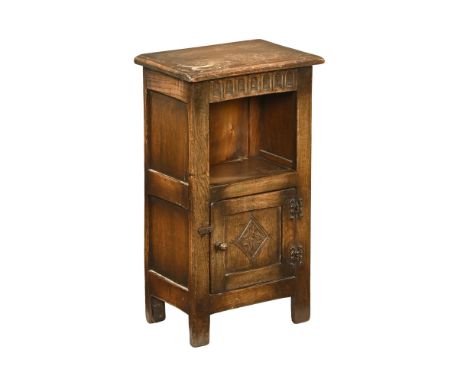 An Ipswich oak style bedside cabinet, with open aperture and carved panelled cupboard door.  Height 68 cm, width 40 cm, depth