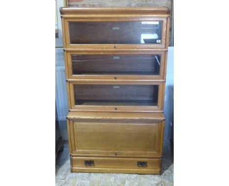 An oak Globe Wernicke stacking bookcase with three glazed sections and one base section with a solid door and a drawer in ori